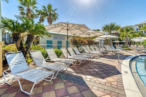 A poolside area with lounge chairs and umbrellas, a sign for Seacrest Beach Cafe, and palm trees. - Palms by the Sea Carriage House | Community Pool | Pets Welcome (Seacrest Beach)