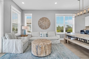 A modern living room with a round coffee table, a sofa, and a dining area with a bench. - ⭐Palms By The Sea | Rooftop Deck | Pool | Beach Access⭐ (Seacrest Beach)