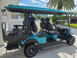 A teal golf cart with a covered seating area, a steering wheel, and a rear luggage rack. - Amazing Waterfront Home 2 Blks 2 Beach & Food (Indian Rocks Beach)
