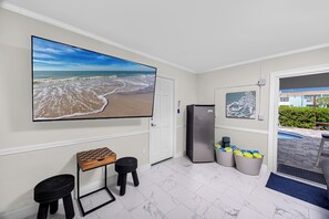 A compact room with a large beach view, a refrigerator, a small table with stools, and a poolside area visible through an open door. - Luxury Waterfront Heated Pool Dock Golf Cart (Indian Rocks Beach)
