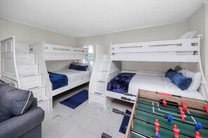 A room with two bunk beds, a desk, drawers, a chair, and a foosball table. - Luxury Waterfront Heated Pool Dock Golf Cart (Indian Rocks Beach)