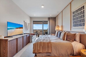 Ein modernes Hotelzimmer mit einem großen Bett, einem Fernseher, einem Schreibtisch und Blick auf die Stadt.