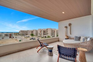 Ein Balkon mit Blick auf ein Wohngebiet, eine Sitzecke mit einer Couch und Stühlen sowie ein kleiner Tisch.