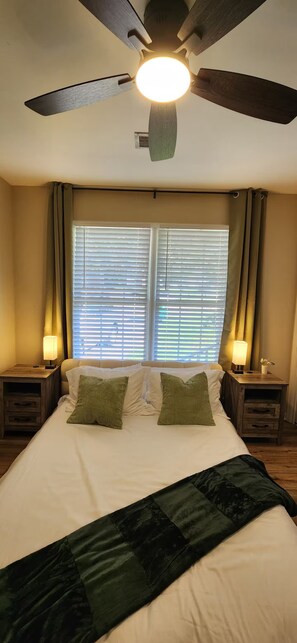 A bedroom with a bed, two bedside lamps, a ceiling fan, and a window with blinds. - Modern 2BR - King Bed - Pet-Friendly - Sleeps 6 (Boiling Springs)