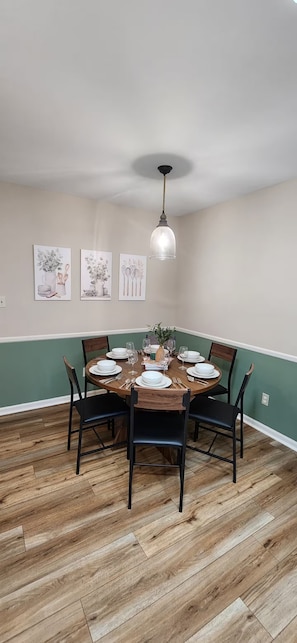A dining area with a round table set for four, surrounded by chairs, and a pendant light above. - Modern 2BR - King Bed - Pet-Friendly - Sleeps 6 (Boiling Springs)