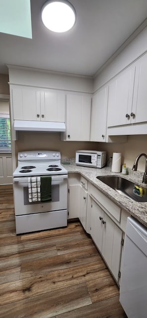 A kitchen with white cabinets, a stove, a microwave, and a sink. - Modern 2BR - King Bed - Pet-Friendly - Sleeps 6 (Boiling Springs)
