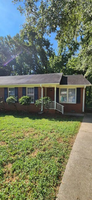 A single-story house with a brick facade, a front porch, and a small front yard. - Modern 2BR - King Bed - Pet-Friendly - Sleeps 6 (Boiling Springs)