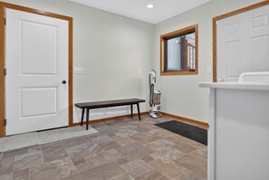 A clean, well-lit hallway with a bench, a vacuum cleaner, and a window. - Massive 5 bed stay for up to 10! Rural and PRIVATE (Billings)