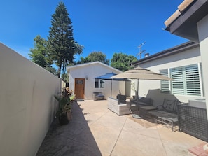 A patio area with a seating arrangement, a door, and a large tree. - Vaulted 12 ft ceilings studio gated with  private bathroom, W/D, walk in closet. (Los Angeles)