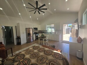 A modern kitchen with white cabinetry, stainless steel appliances, and a ceiling fan. - Vaulted 12 ft ceilings studio gated with  private bathroom, W/D, walk in closet. (Los Angeles)