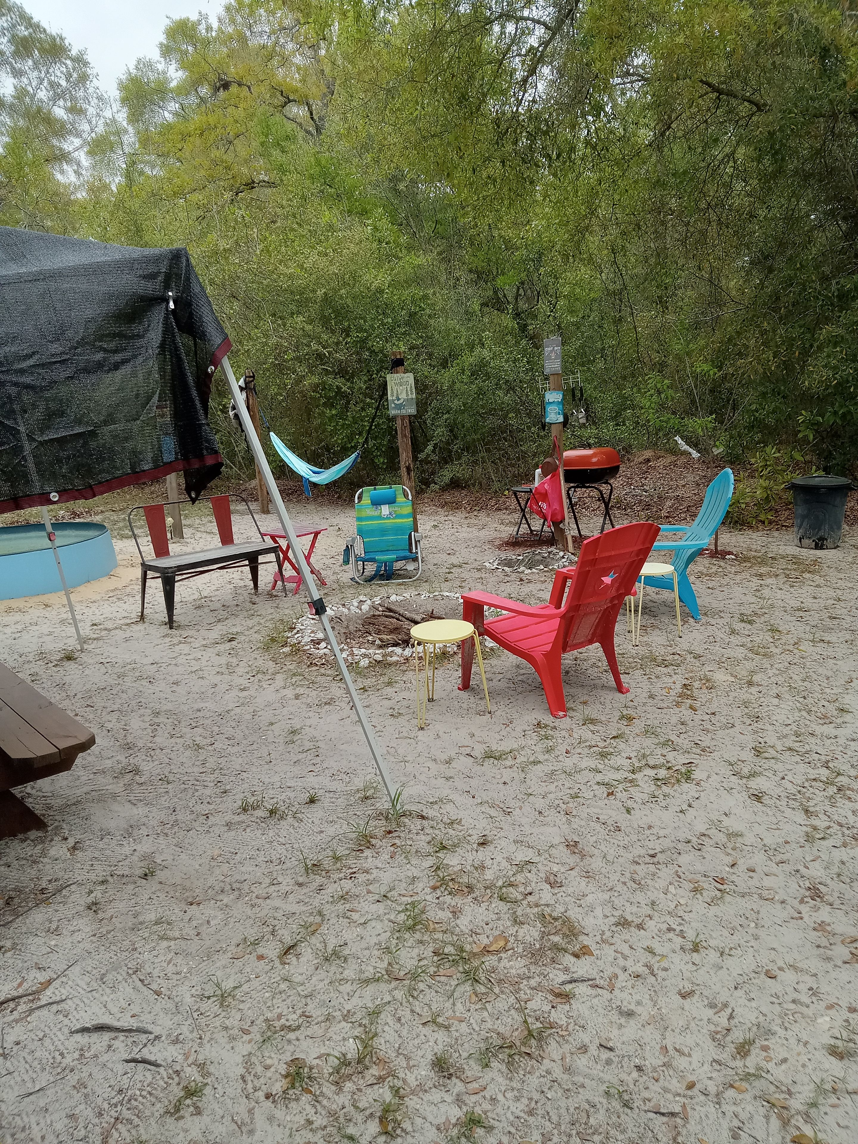 An outdoor seating area with a hammock, picnic table, and various chairs.