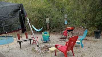 An outdoor seating area with a hammock, picnic table, and various chairs.