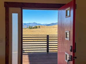 A doorway leading to a deck with a view of a grassy field and mountains. - CGOs Lookout A spacious 2-bedroom 2 king beds 2 bath house in Emigrant (Emigrant)