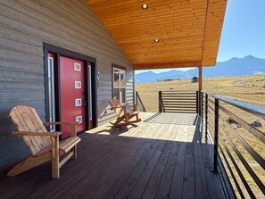 A wooden deck with Adirondack chairs, a red door, and a view of mountains. - CGOs Lookout A spacious 2-bedroom 2 king beds 2 bath house in Emigrant (Emigrant)