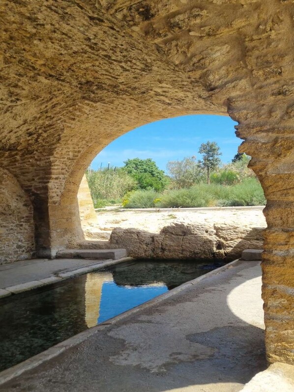 An arched stone structure with a pool underneath.