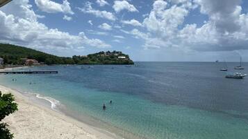 Una playa costera con aguas transparentes, un muelle y embarcaciones.