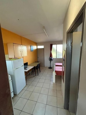 Una cocina compacta con refrigerador, una mesa de comedor y una silla.