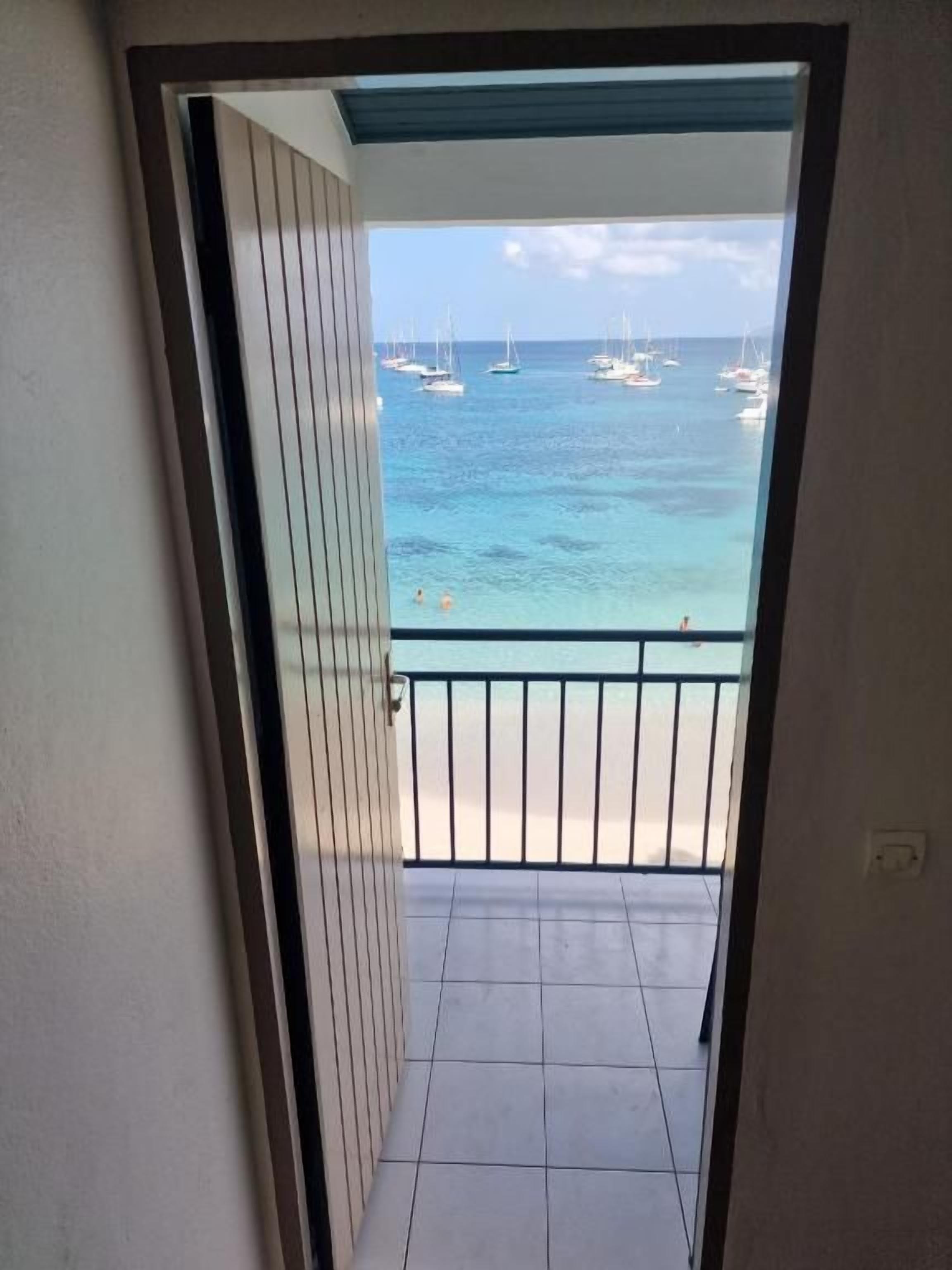 A view from a balcony to a beach with boats and a clear sky.