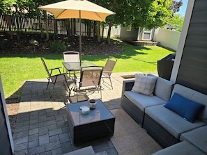 An outdoor patio with a table and chairs, a sofa, and a large umbrella. - Delightful, walkable 4-bedroom family home (Coeur d'Alene)
