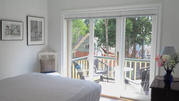 Un dormitorio con cama, ventana con vista a un balcón y dos cuadros en la pared.