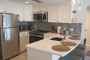 Una cocina moderna con electrodomésticos de acero inoxidable, microondas y una isla grande con pileta.
