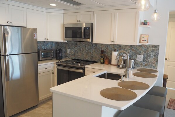 A modern kitchen with stainless steel appliances, a microwave, and a large island with a sink.