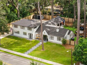 A two-story house with a well-maintained lawn, a swing set, and a fenced backyard. - Sandbar Grand Estate, 4-Bedroom Luxury Retreat Near the University of Florida (Gainesville)