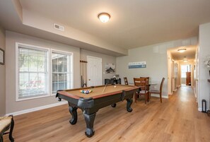Een pooltafel in een kamer met een houten vloer, een deur en een bord waarop staat 'Welcome to the Lake'.