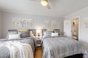 A bedroom with two beds, a ceiling fan, and artwork on the walls. - Updated Coastal Retreat w/ Pool Near Beach! (Hilton Head Island)
