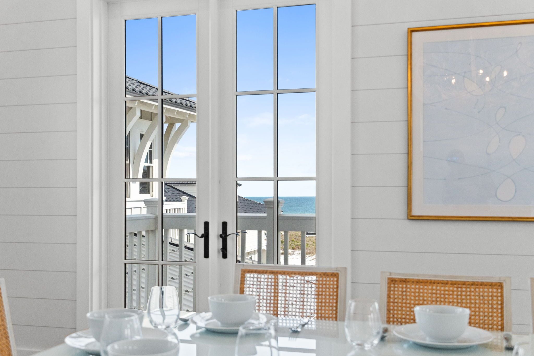 Picture yourself enjoying morning coffee at this elegant dining table, with the bright blue sea framing your view through tall French doors. Coastal elegance meets comfortable living.