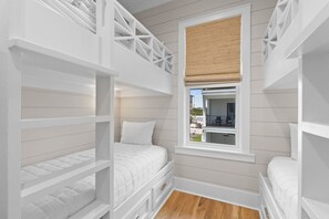 A room with bunk beds, a window with a view, and a wooden floor. - Stunning 6 Bedroom Sugar Sands Home, Private Pool, Sleeps 14 (Mexico Beach)