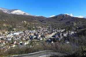 A town nestled in a valley with snow-capped mountains in the background. - Ski aux pieds | Piscine chauffee sur place (Ax-les-Thermes)