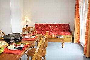 Ein Essbereich mit Tisch für zwei Personen, einer Couch und einer Lampe.