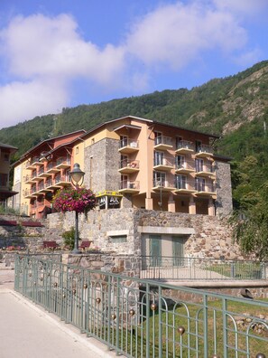 Un hôtel à plusieurs étages doté de balcons, d’une façade en pierre et surplombant un paysage montagneux.