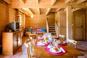 Un intérieur en bois avec une table à manger dressée pour le petit-déjeuner, un canapé et un escalier.
