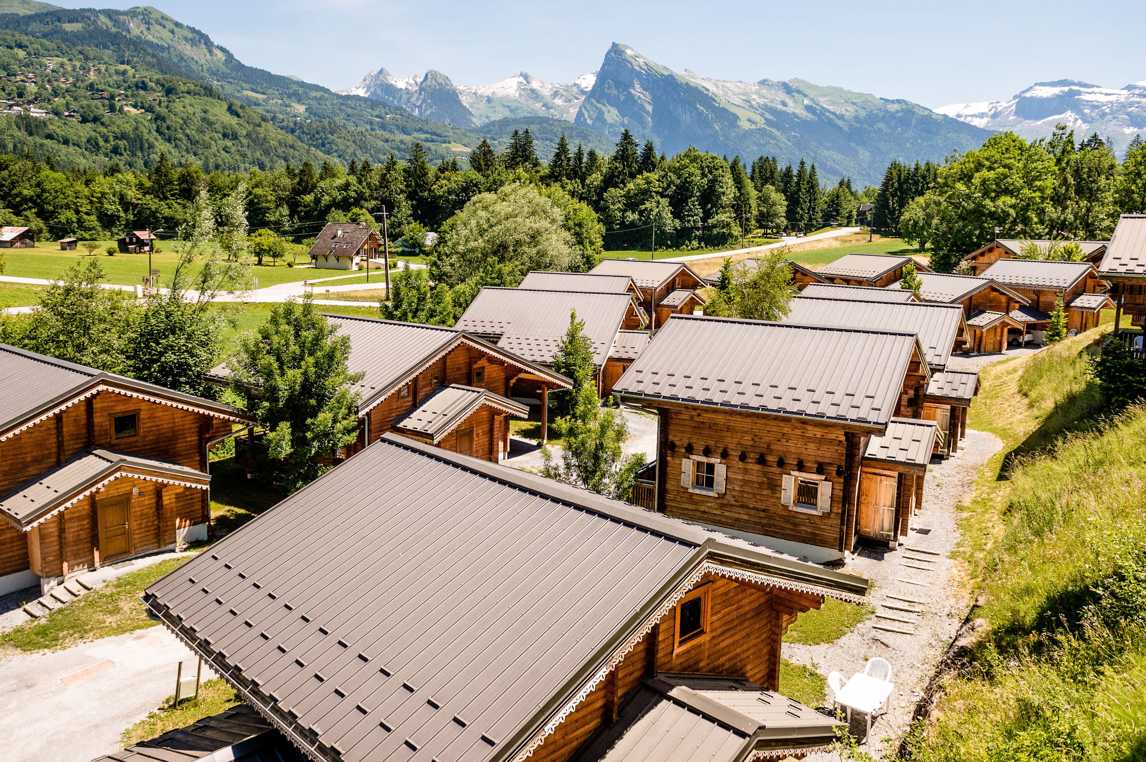 Un grupo de cabañas de madera con techos inclinados, rodeadas por un paisaje montañoso.