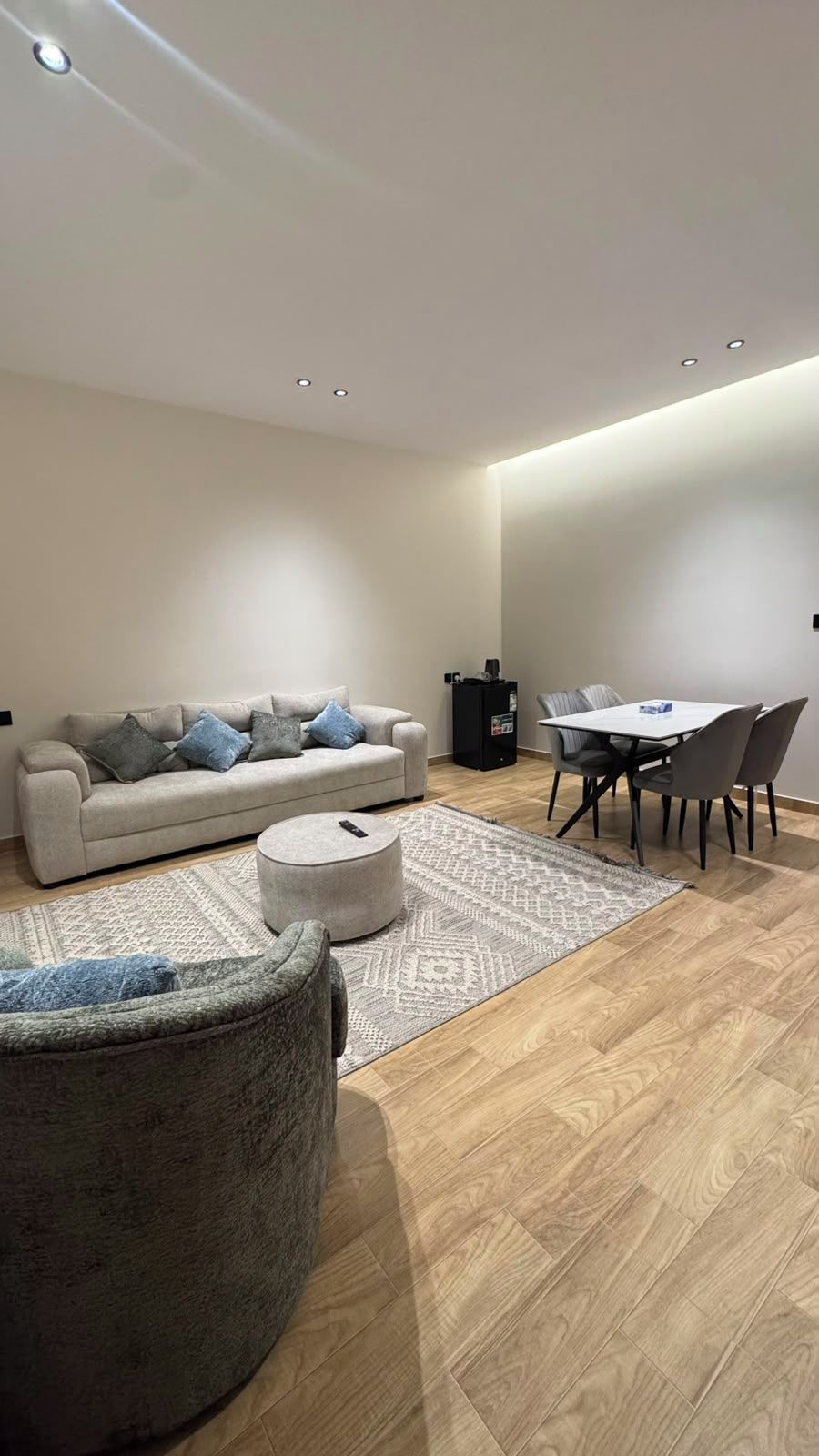 A modern living room with a sofa, ottoman, and dining table.