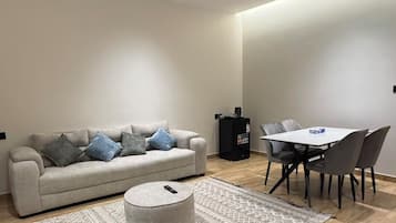 A modern living room with a sofa, ottoman, and dining table.