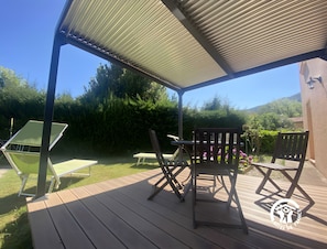An outdoor patio with a covered seating area, a table, and chairs.