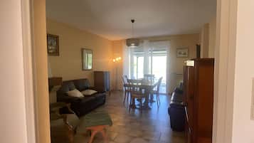 Un grand espace de vie comprenant un canapé, une table à manger avec des chaises et un escalier menant à un autre niveau.