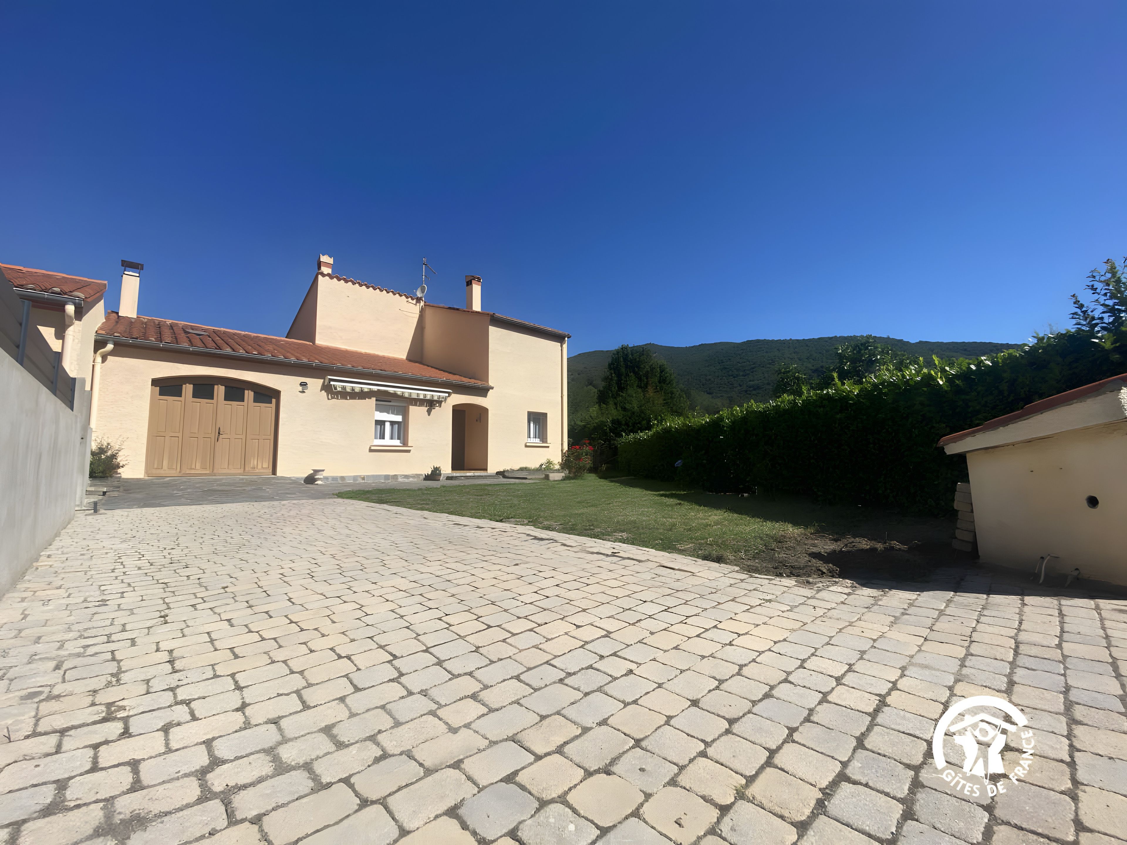 Une maison à deux étages avec une allée pavée, un grand portail de garage et une pelouse bien entretenue.