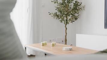 A minimalist room with a white wall, a wooden table with a few items, and a small plant.