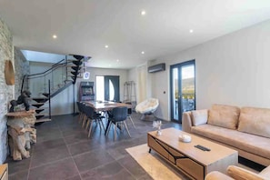 Ein geräumiger Wohnbereich mit Sofa, Esstisch und einer Treppe.