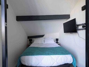 Ein Schlafzimmer mit einem Bett, Nachttischen, einem an der Wand befestigten Fernseher und einer Wandleuchte.