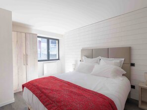 A bedroom with a bed, a window, a wardrobe, and a bedside table. - Les Terrasses du Lac -lake/mountain views, hot tub (Chanaz)