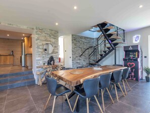 Eine moderne Küche mit einer Steinwand, einem Holztisch mit Stühlen und einer Treppe mit Glastrennwand.