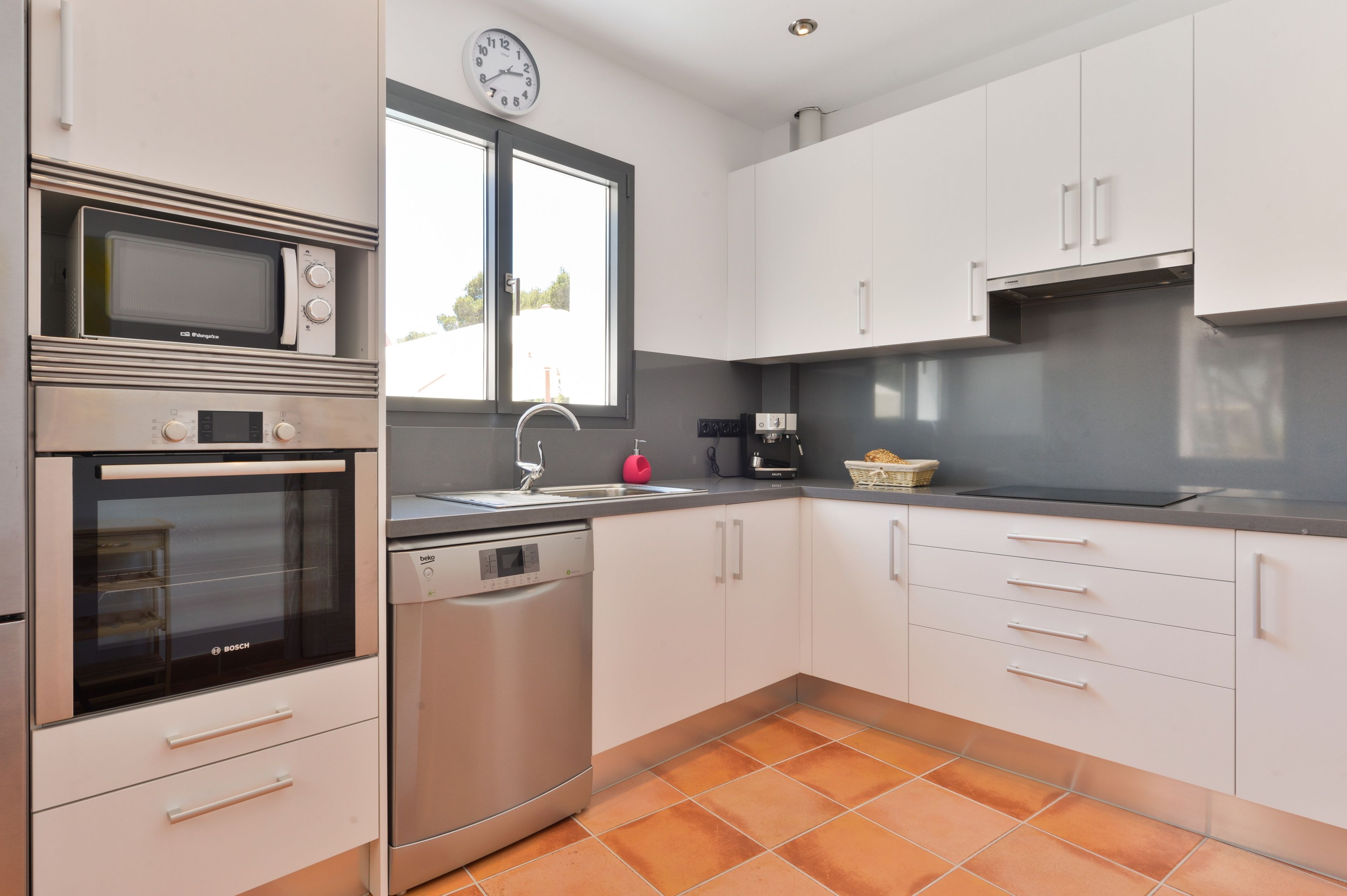 A modern kitchen with stainless steel appliances, a dishwasher, and a window with a view.