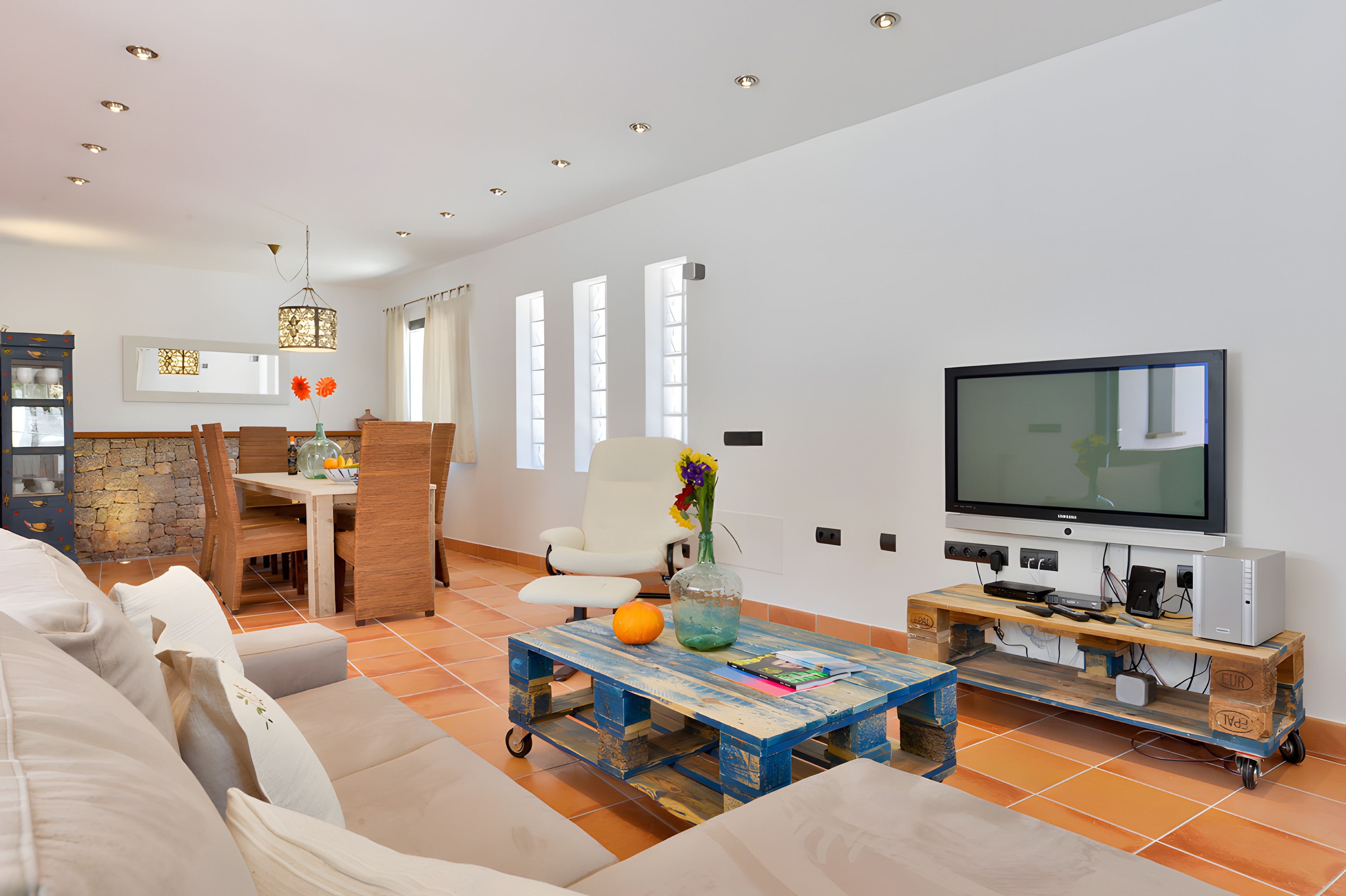 Una sala de estar moderna con un sofá, una mesa de centro, un televisor y un comedor con una mesa y sillas.