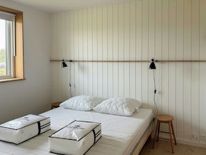 Ein Schlafzimmer mit einem Bett, zwei Nachttischlampen, einem hölzernen Hocker und Aufbewahrungsboxen.