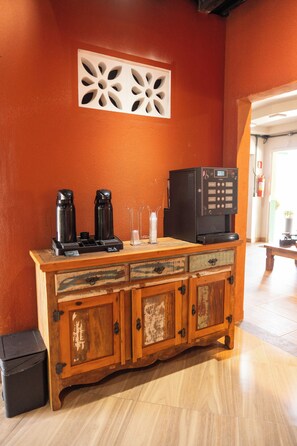 A wooden bar area with a coffee machine, a microwave, and a small refrigerator.